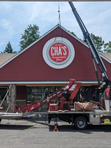 NH Signs - retail sign being hung on building by a crane